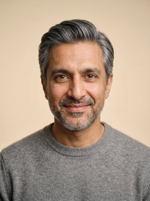 Professional studio headshot of a 40-year-old Pakistani man with silver-streaked dark hair combed ba