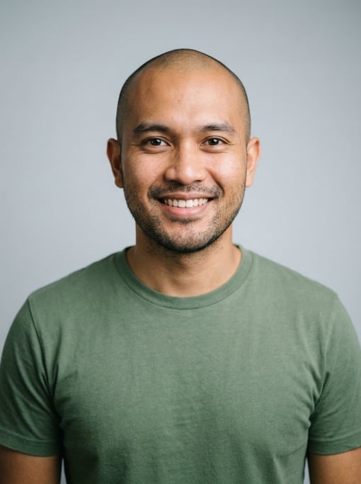 Professional studio headshot of a 28-year-old Indonesian man with a shaved head