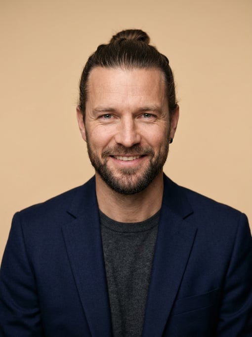 Professional studio headshot of a 40-year-old White Nordic man with a man bun in dark brown