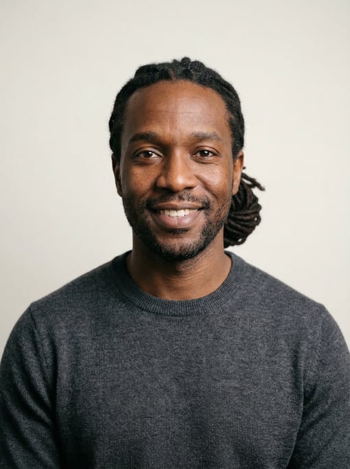 Professional studio headshot of a 38-year-old Black American man with medium dreadlocks pulled back