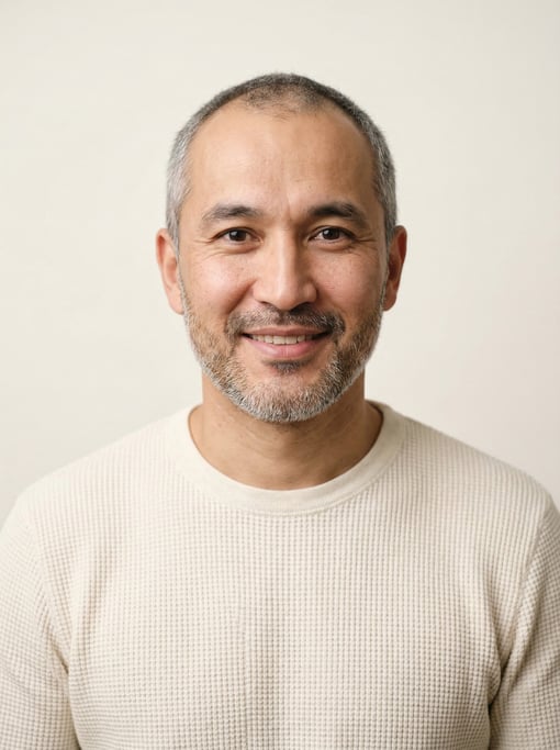 Professional studio headshot of a 34-year-old Central Asian man with receding hairline with short gr