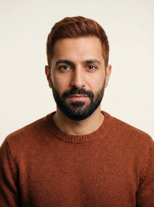 Professional studio headshot of a 33-year-old Persian man with short red-brown hair