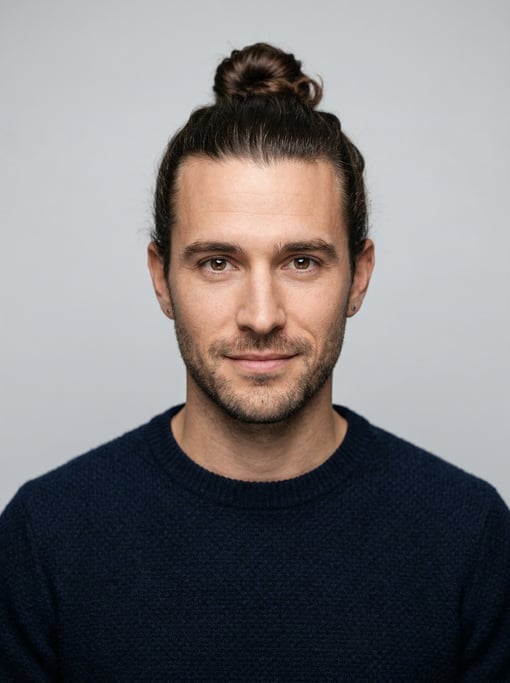 Professional studio headshot of a 29-year-old White European man with a man bun in dark brown
