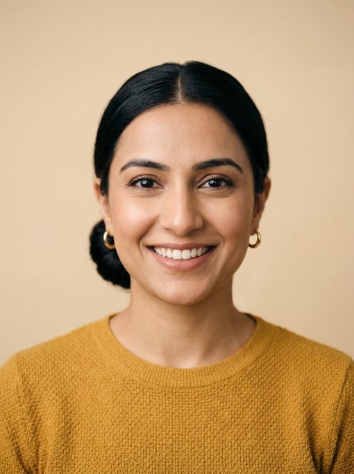 Professional studio headshot of a 29-year-old Pakistani woman with a sleek low bun in black