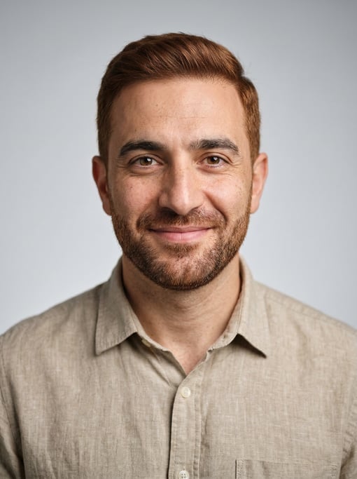 Professional studio headshot of a 40-year-old Middle Eastern man with short red-brown hair