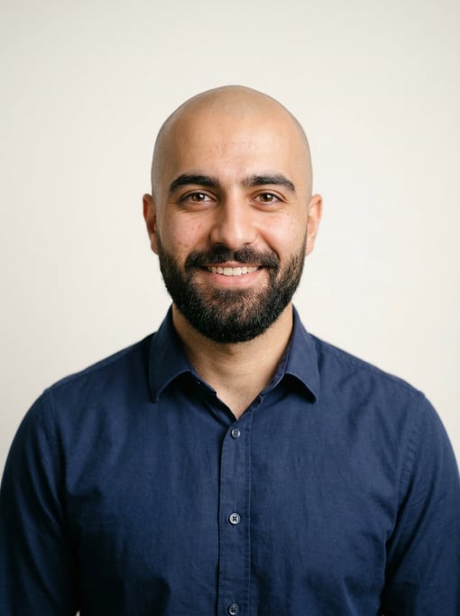 Professional studio headshot of a 25-year-old Persian man with a shaved head