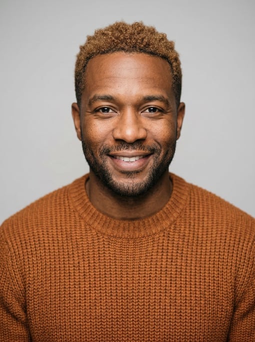 Professional studio headshot of a 34-year-old Black American man with short cropped sandy brown hair