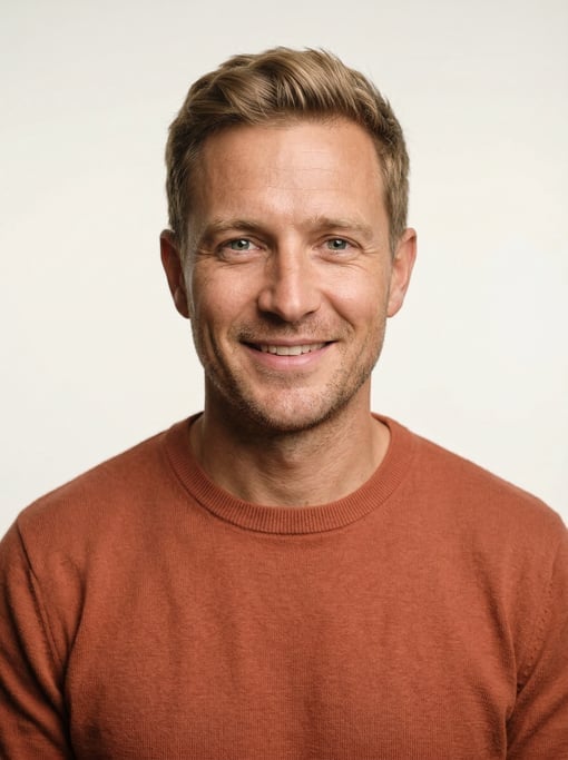 Professional studio headshot of a 34-year-old White British man with short dirty blonde hair