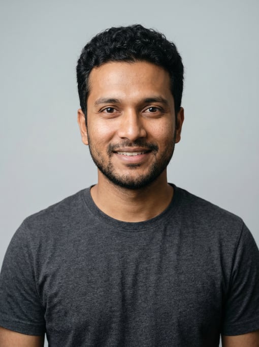 Professional studio headshot of a 25-year-old Bengali man with short curly black hair