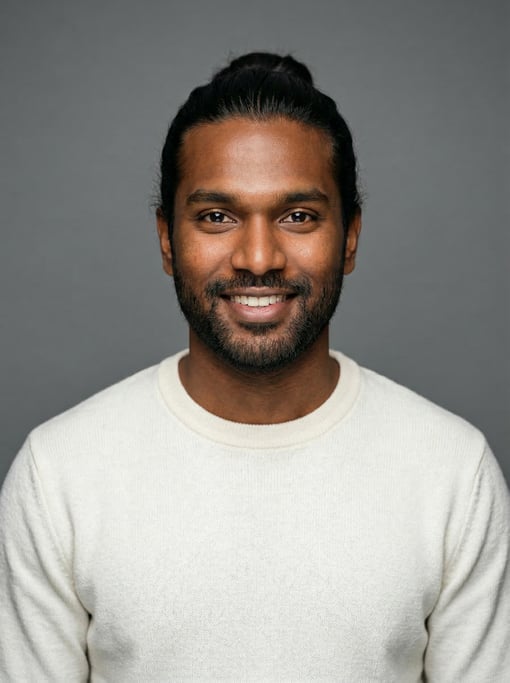 Professional studio headshot of a 25-year-old West African man with long straight black hair tied ba