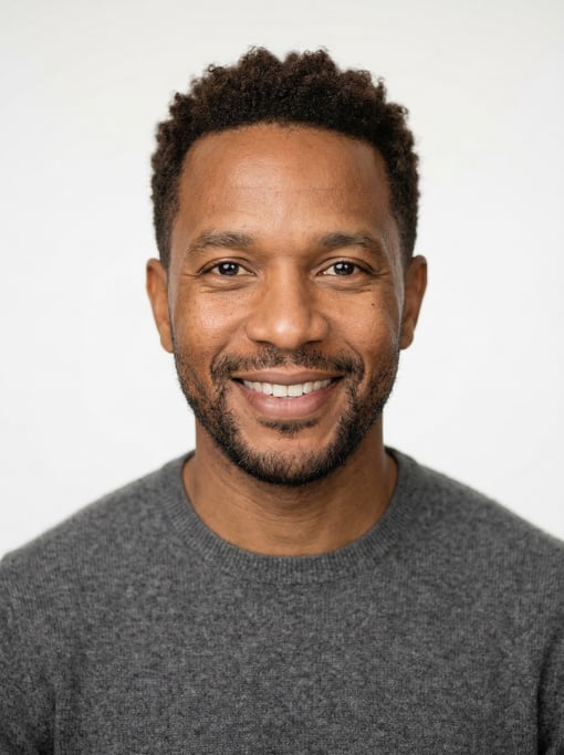 Professional studio headshot of a 39-year-old Jamaican man with short textured dark brown hair