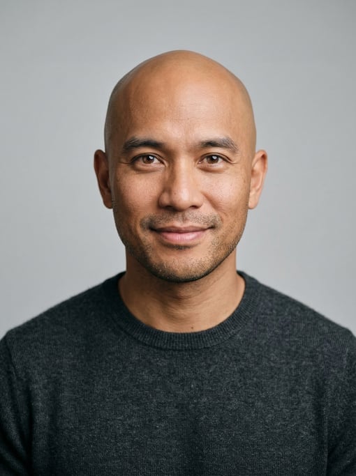 Professional studio headshot of a 38-year-old Southeast Asian man with a completely bald head
