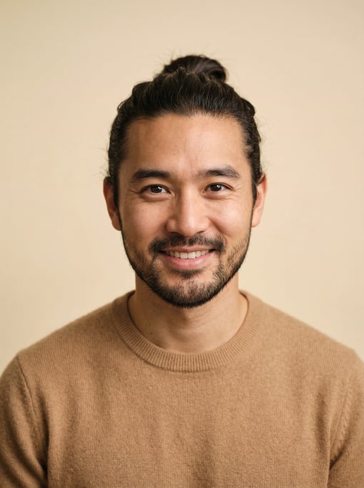 Professional studio headshot of a 30-year-old East Asian man with a man bun in dark brown