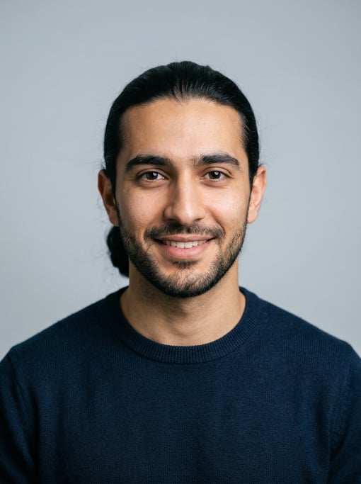 Professional studio headshot of a 24-year-old Middle Eastern man with long straight black hair tied