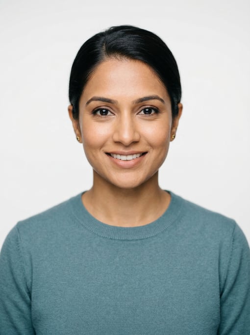 Professional studio headshot of a 30-year-old South Asian woman with a sleek low bun in black