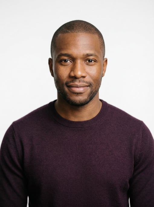 Professional studio headshot of a 34-year-old Black African man with a buzz cut in brown