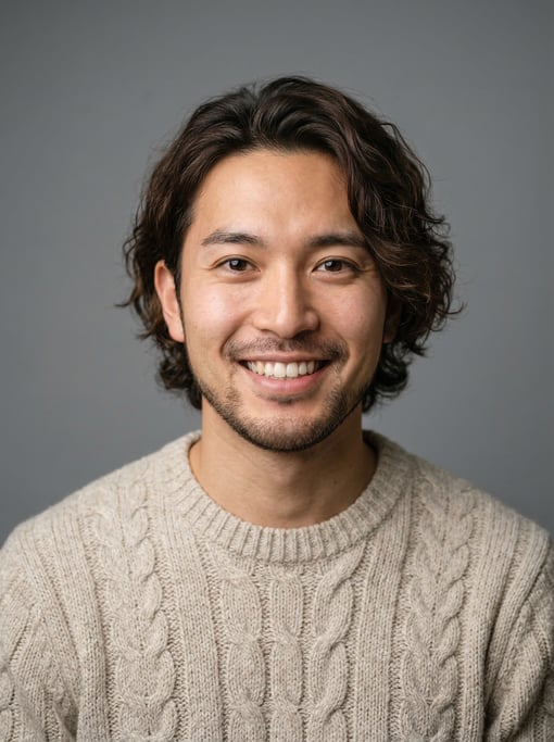 Professional studio headshot of a 25-year-old Japanese man with medium-length wavy dark brown hair