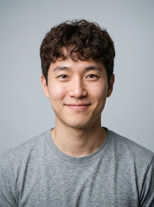 Professional studio headshot of a 24-year-old Korean man with short curly dark brown hair