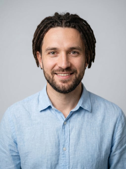 Professional studio headshot of a 35-year-old White Eastern European man with short locs in dark bro