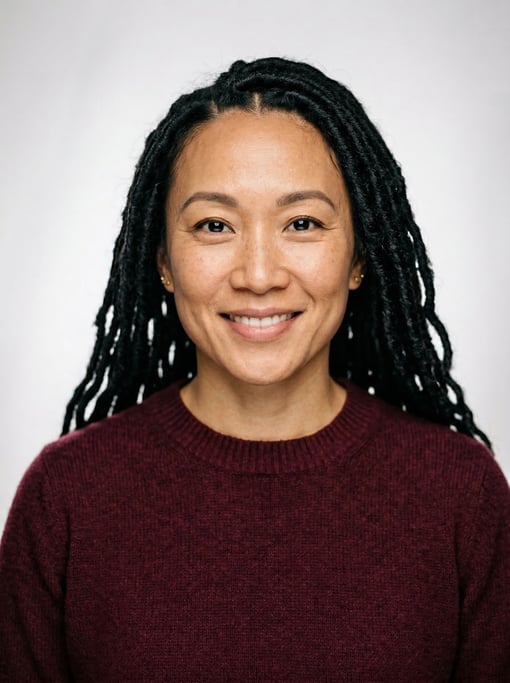 Professional studio headshot of a 39-year-old East Asian woman with long faux locs in black