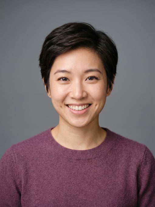 Professional studio headshot of a 25-year-old East Asian woman with a short pixie cut in dark brown