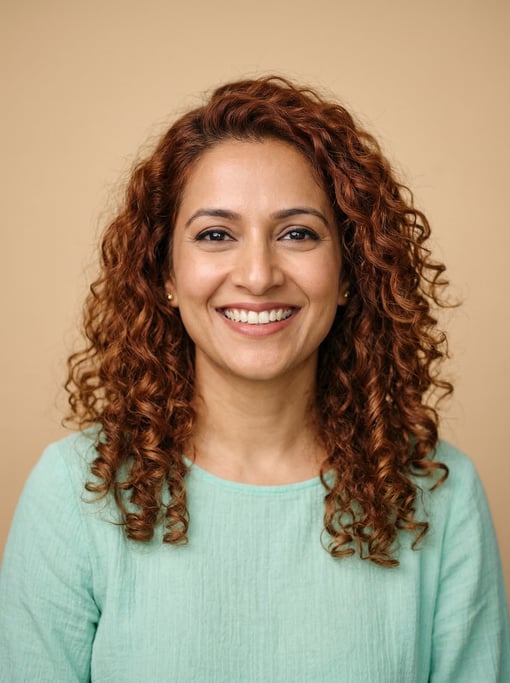 Professional studio headshot of a 37-year-old Indian woman with shoulder-length curly auburn hair