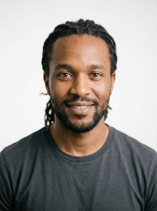 Professional studio headshot of a 33-year-old East African man with medium dreadlocks pulled back
