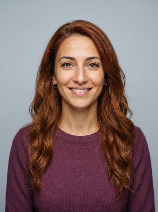 Professional studio headshot of a 34-year-old Lebanese woman with long wavy auburn hair