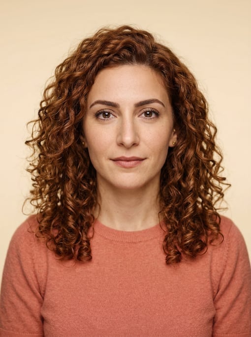 Professional studio headshot of a 34-year-old Lebanese woman with shoulder-length curly auburn hair