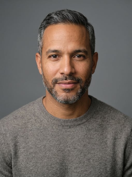 Professional studio headshot of a 33-year-old Dominican man with short salt-and-pepper hair neatly c