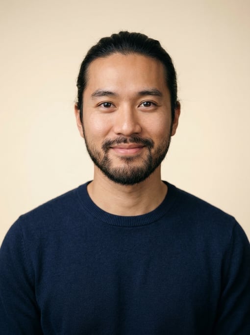 Professional studio headshot of a 28-year-old Vietnamese man with long straight black hair tied back