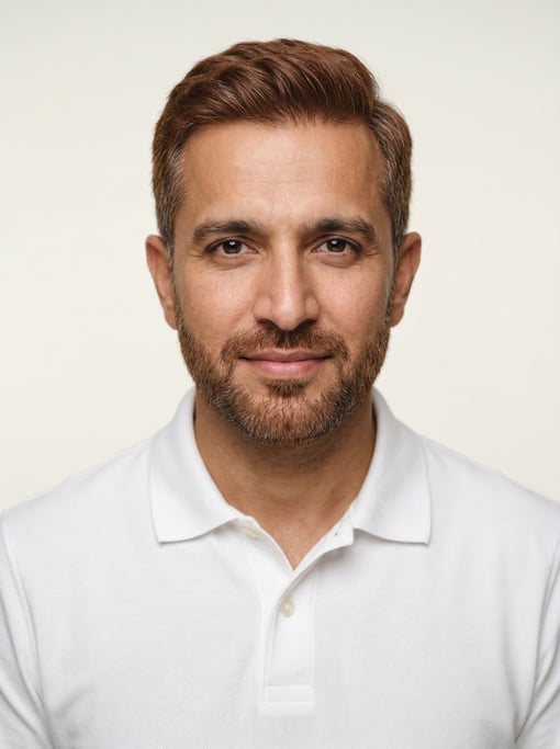 Professional studio headshot of a 38-year-old Pakistani man with short red-brown hair