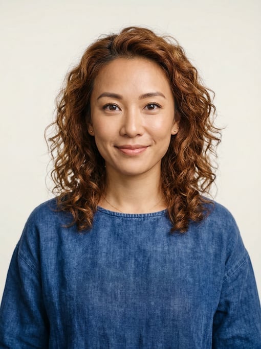 Professional studio headshot of a 32-year-old Chinese woman with shoulder-length curly auburn hair