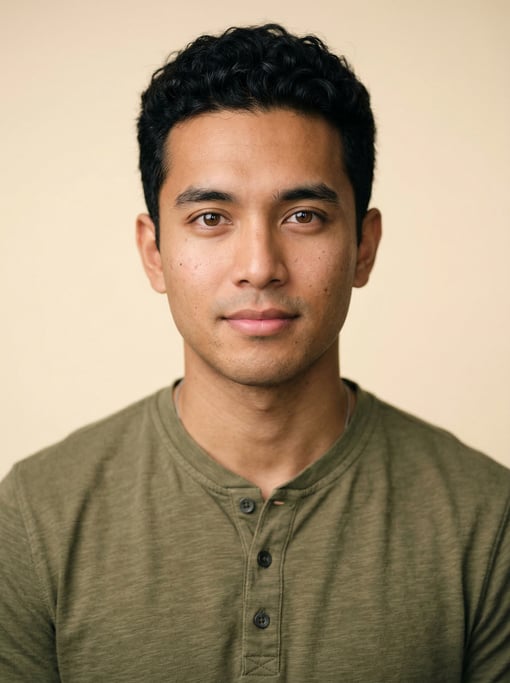 Professional studio headshot of a 27-year-old Southeast Asian man with short curly black hair