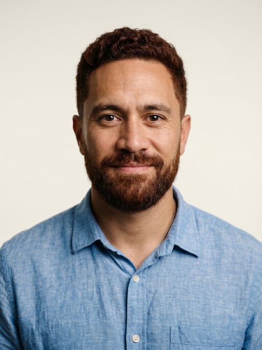 Professional studio headshot of a 34-year-old Maori man with short red-brown hair
