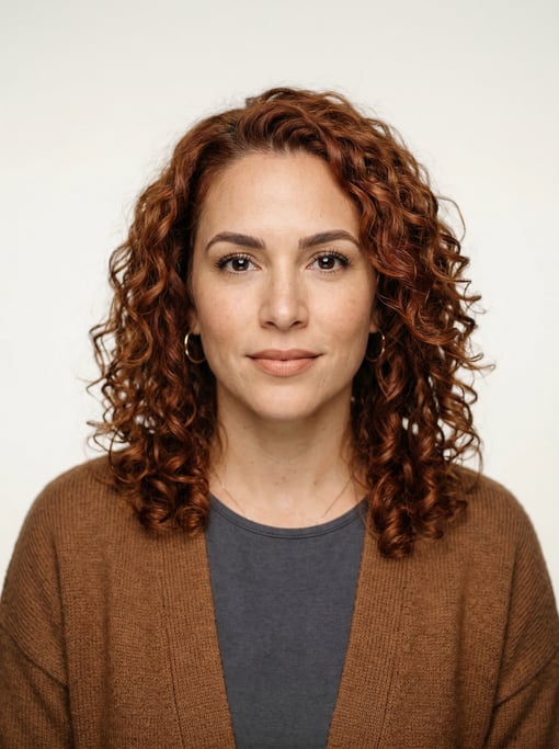 Professional studio headshot of a 36-year-old Puerto Rican woman with shoulder-length curly auburn h