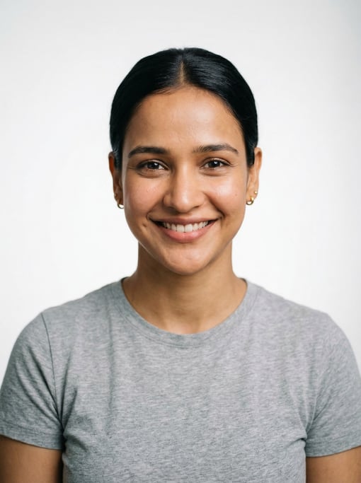 Professional studio headshot of a 24-year-old Indian woman with a sleek low bun in black