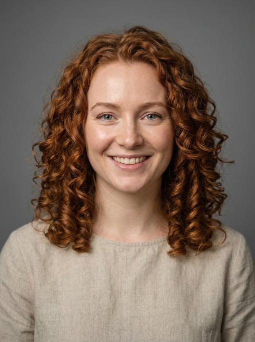 Professional studio headshot of a 25-year-old White British woman with shoulder-length curly auburn