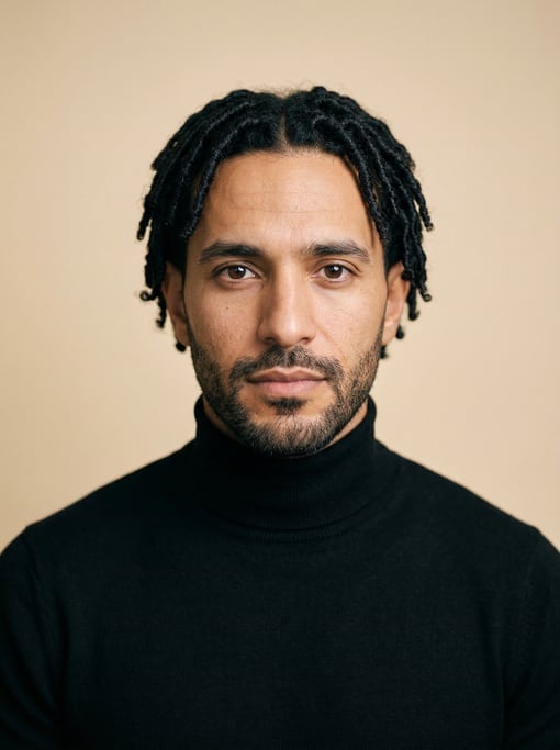 Professional studio headshot of a 33-year-old Middle Eastern man with short locs in black