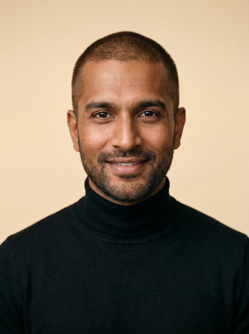 Professional studio headshot of a 35-year-old Indian man with a buzz cut in brown
