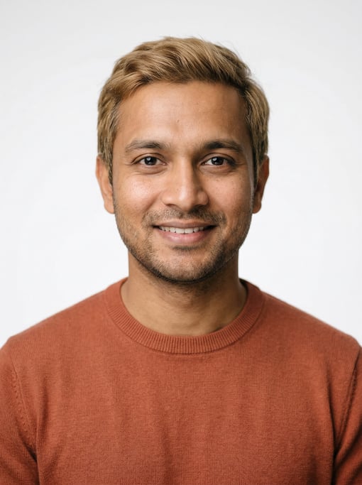 Professional studio headshot of a 31-year-old Bengali man with short dirty blonde hair