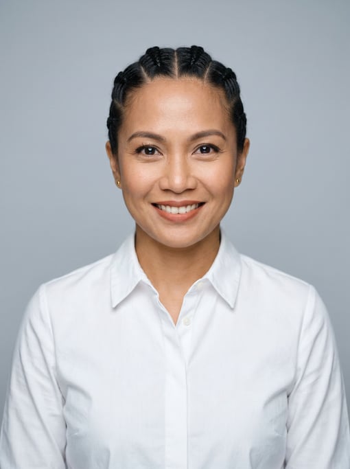 Professional studio headshot of a 38-year-old Southeast Asian woman with cornrows pulled back neatly