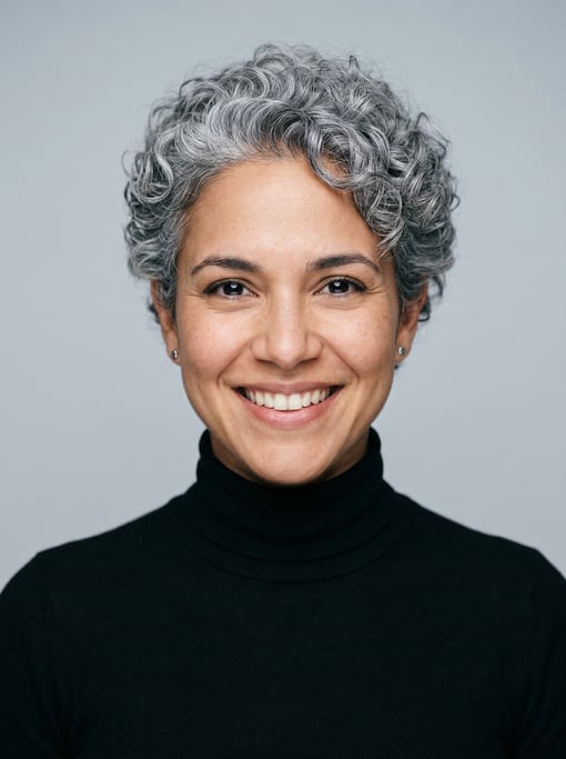 Professional studio headshot of a 32-year-old Cuban woman with a short curly silver-grey crop