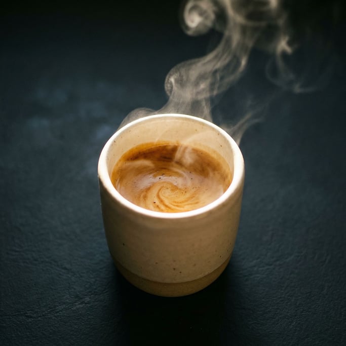 An espresso shot in a thick ceramic cup, crema still swirling