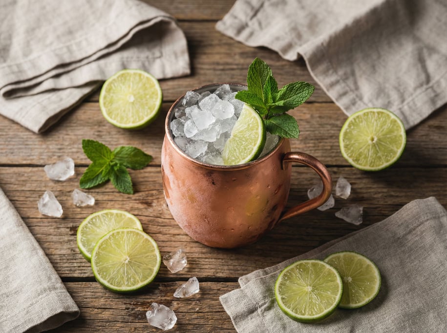 A copper Moscow mule mug with crushed ice and lime, condensation frost on the outside (r6p5fyt2)