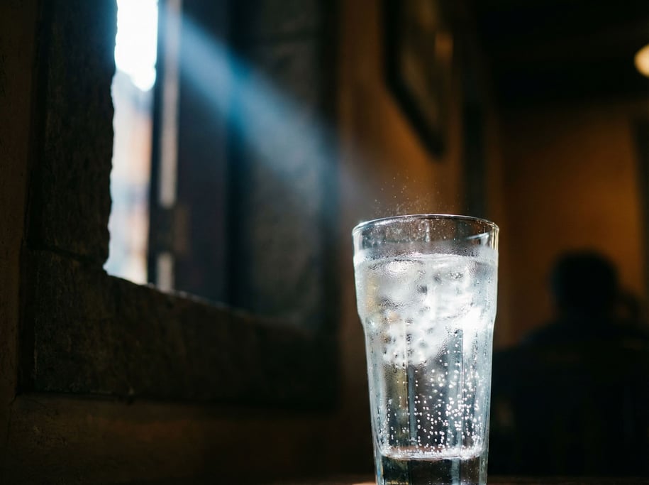 A clear glass of sparkling water with ice, condensation on the glass, cool light (lkswtsjr)