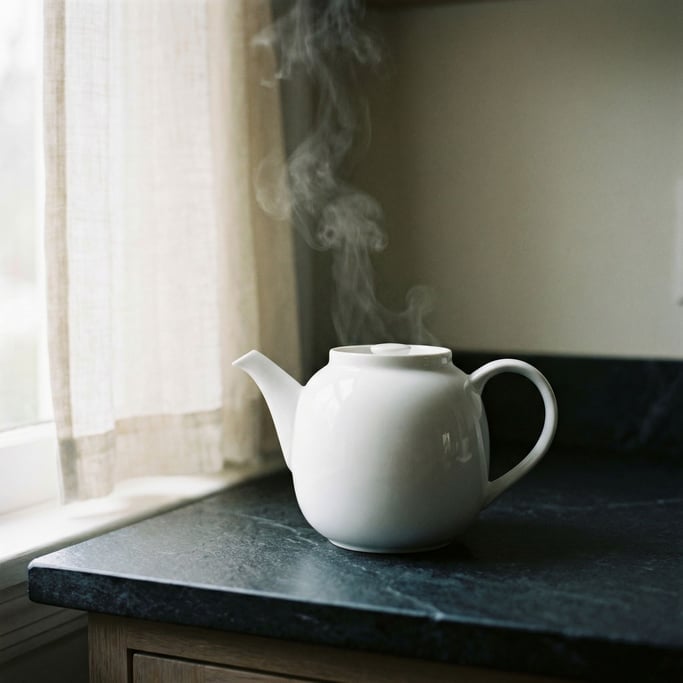 A white porcelain teapot on a dark stone counter, steam rising, minimal and clean (xzmxp1y)