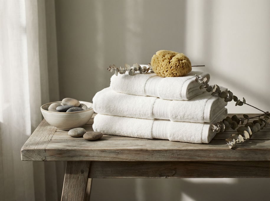 A stack of white cotton towels on a teak bench, spa-like simplicity, neutral tones (47jrtloz)