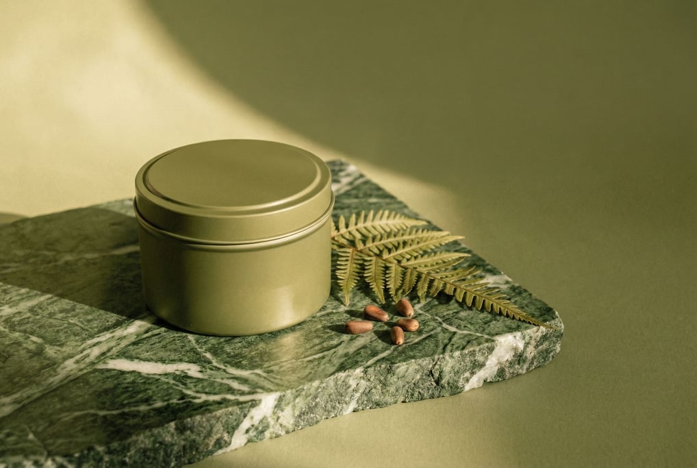 A vintage-style tin candle with a slip lid in matte olive on a rough-cut piece of green marble with white veining