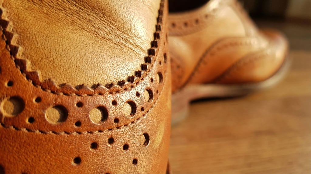 Each tiny punched hole in a leather brogue tells two stories — the smooth interior leather visible t